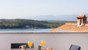 Uma sala de jantar com mesa posta para o café da manhã, com vista para um lago e montanhas.