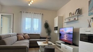 Uma sala de estar moderna com um sofá, TV e uma planta.
