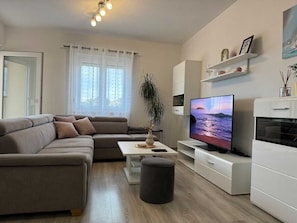 A modern living room with a sofa, TV, and a plant. - Apartment Maticic gore (Šilo)