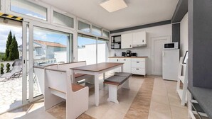 A modern kitchen with a dining area, large windows, and a view of the outside. - Apartment Maria Zestilac (Žestilac)