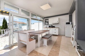 Eine moderne Küche mit Essbereich, großen Fenstern und Blick ins Freie.