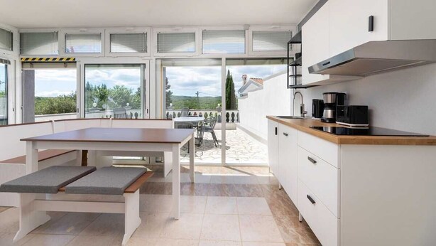 Een moderne keuken met een eethoek, grote ramen en uitzicht op de omgeving.