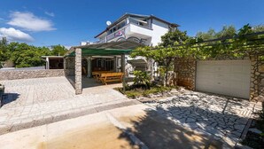A two-story house with a stone facade, a covered patio, and a garage. - Apartment Maria Zestilac (Žestilac)