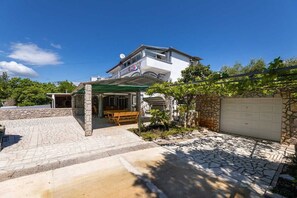 Ein zweistöckiges Haus mit einer Stein-Fassade, einer überdachten Terrasse und einer Garage.
