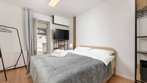 A neatly arranged bedroom with a bed, a television, a wardrobe, and a drying rack. - Apartment Maria Zestilac (Žestilac)