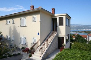 A two-story building with a staircase, outdoor seating, and a view of the landscape. - Apartment Dvornicic A4 (Šilo)