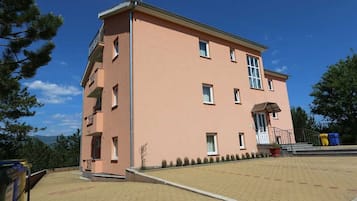 Ein mehrstöckiges Gebäude mit flachem Dach, einem Balkon im zweiten Stockwerk und einem gepflasterten Innenhof.