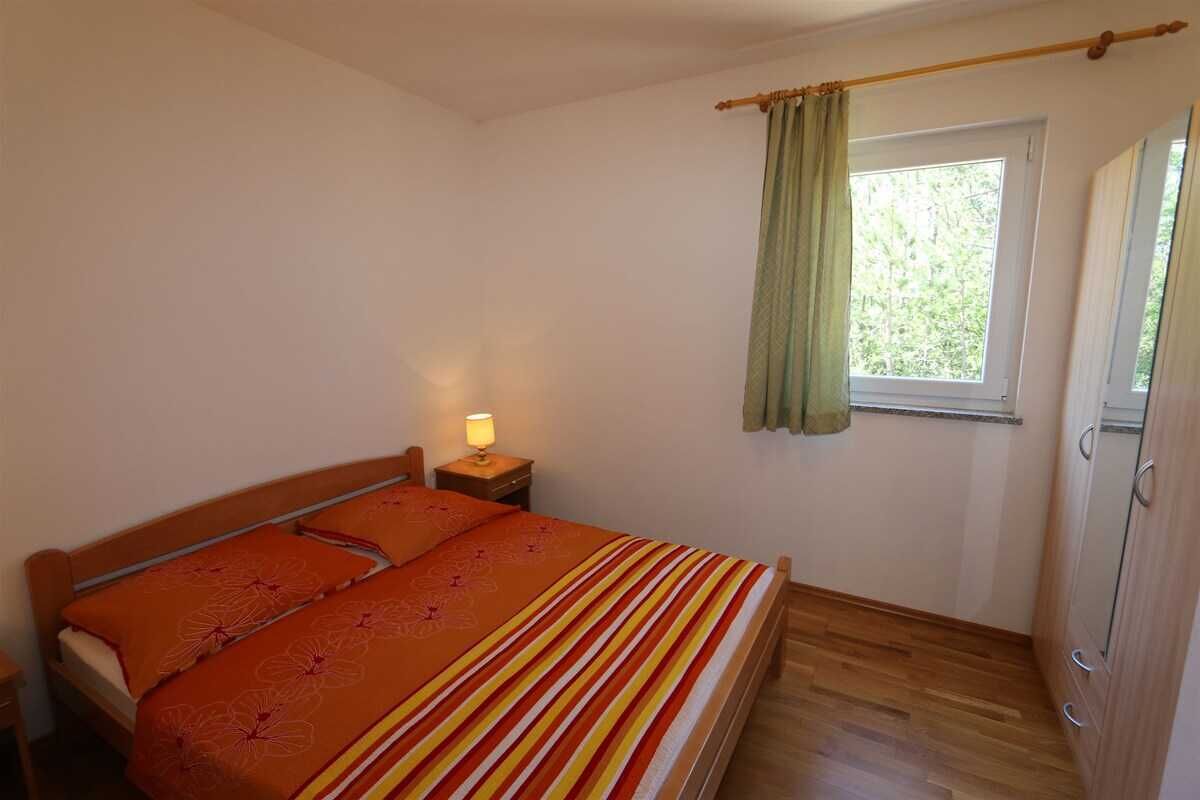 Une chambre à coucher comprenant un lit, une table de chevet, une fenêtre avec des rideaux et une armoire.