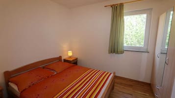 Una camera da letto con un letto, un comodino, una finestra con tende e un armadio.