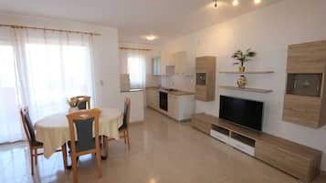 Una cucina moderna con zona pranzo, TV a schermo piatto e scaffali a incasso.