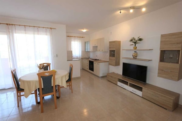 Una cucina moderna con zona pranzo, TV a schermo piatto e scaffali a incasso.