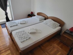 A double bed with patterned pillows and a bedside table with a lamp.