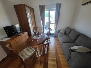 A living room with a sofa, a dining table with chairs, a TV on a stand, and a cabinet. - Apartment Oly Soline nr 4 (Soline)