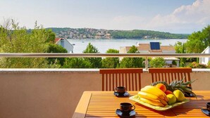 Un balcón con una mesa lista para el desayuno, con vista a un lago y un pueblo.
