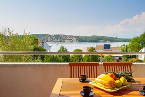 Ein Balkon mit gedecktem Tisch für das Frühstück, mit Blick auf einen See und eine Stadt.