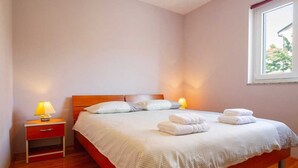 Un dormitorio con una cama, dos lámparas de noche, una mesita de noche y una ventana.