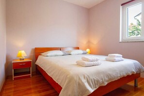 A bedroom with a bed, two bedside lamps, a nightstand, and a window. - Apartment Ana-Soline (Soline)