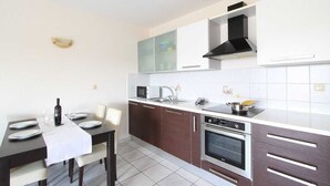 Una cocina moderna con una mesa de comedor para dos personas, un microondas, una estufa y un fregadero.