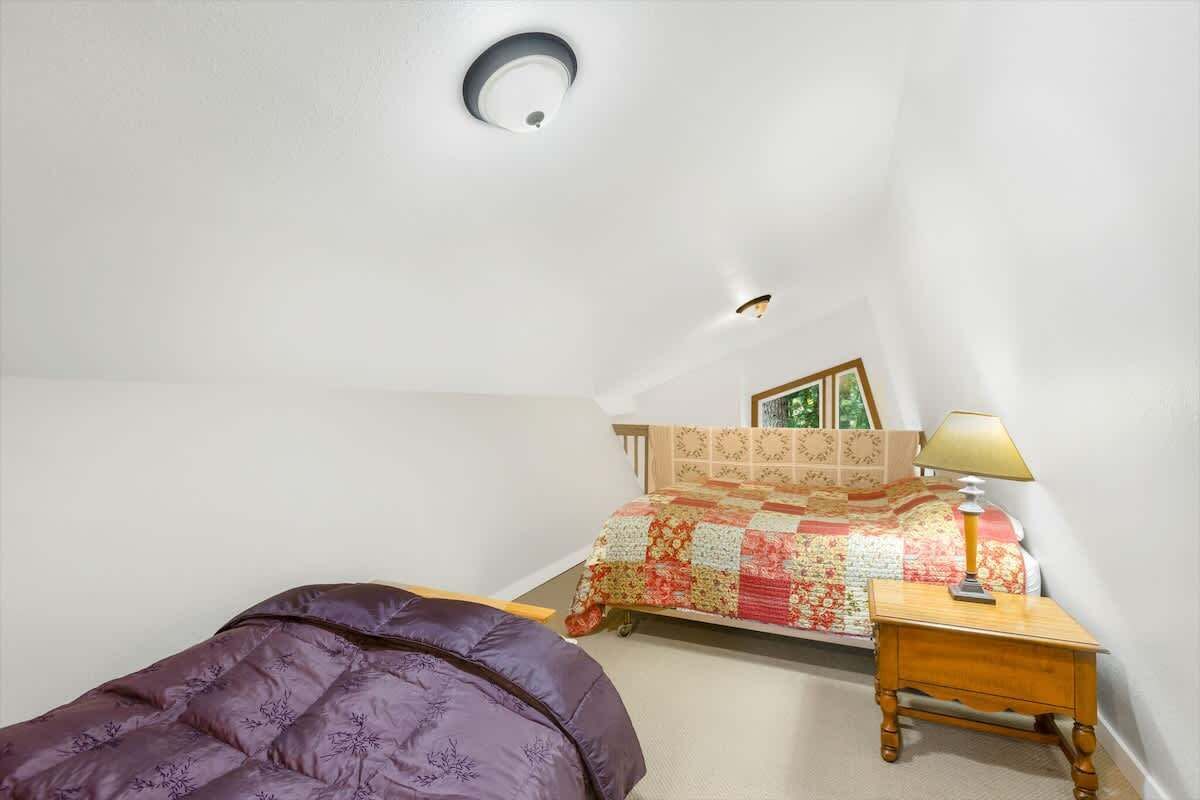 Une chambre à coucher avec un lit, une table de chevet, une lampe, un luminaire au plafond et une fenêtre.