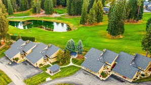 A residential area with multiple houses, a golf course, and a pond.