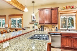 A kitchen with granite countertops, wooden cabinets, a gas stove, and a dishwasher. - Leavenworth Luxury Condo | Fireplace | Porch & BBQ (Leavenworth)