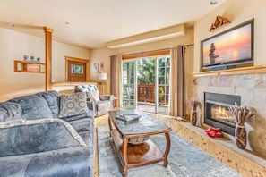 A living room with a sofa, coffee table, fireplace, and a TV mounted above it. - Leavenworth Luxury Condo | Fireplace | Porch & BBQ (Leavenworth)