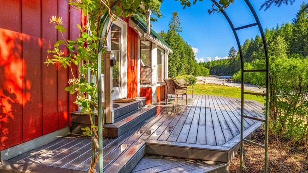 Eine Holzterrasse mit Stufen, die zu einem Haus mit roter Fassade führen.