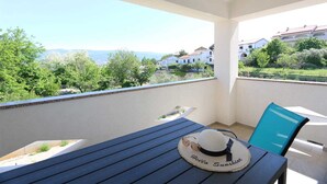 Een balkon met een tafel, een stoel, een hoed en zonnebril.