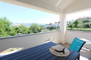 Ein Balkon mit Tisch, Stuhl, Hut und Sonnenbrille.