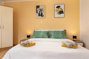 A hotel room with a bed, two nightstands, a wardrobe, and two wall-mounted artworks. - Apartment Adela bijeli (Polje)