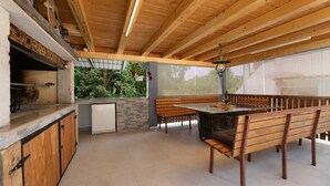 Interior em madeira com bancada de pedra, uma pequena geladeira e uma área de refeições com bancos.
