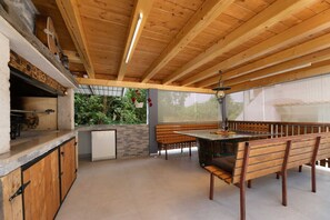 A wooden interior with a stone countertop, a small refrigerator, and a dining area with benches. - Apartment Adela bijeli (Polje)