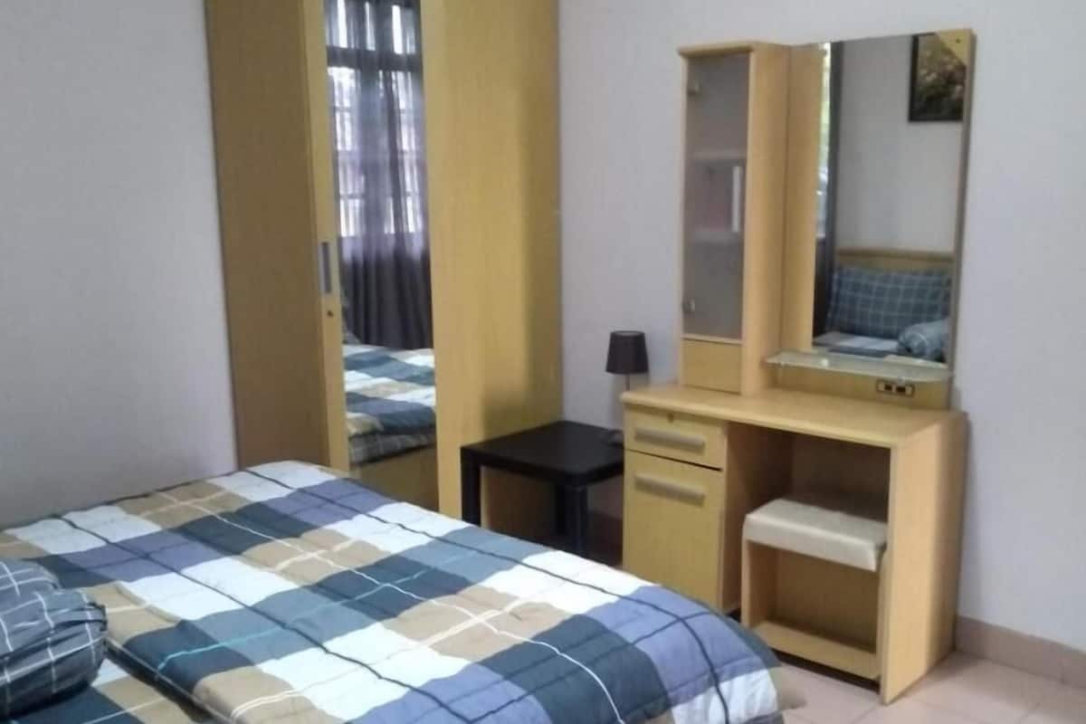 A bedroom with a bed, a wardrobe, a desk, and a mirror.