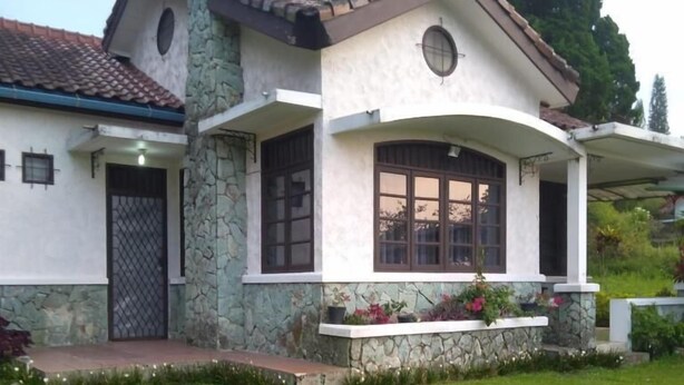 Una casa con fachada de piedra, un porche delantero y un césped bien cuidado.