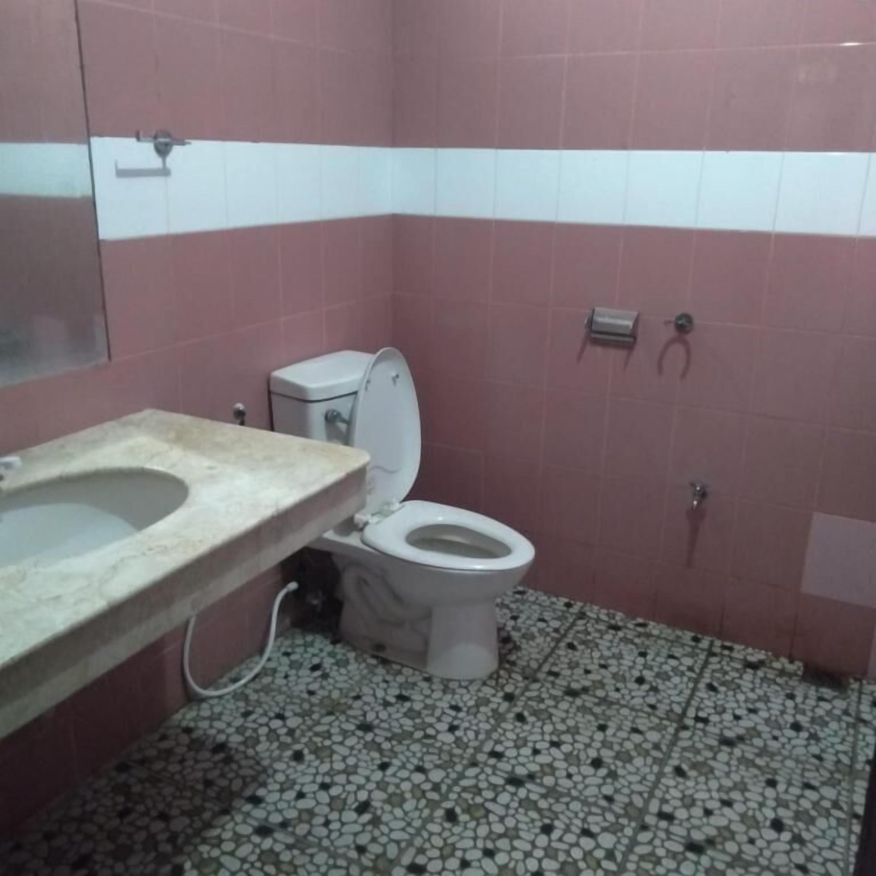 Ein Badezimmer mit Toilette, Waschbecken und Fliesenboden.