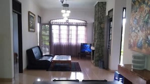 Un área de comedor con una mesa y sillas, un sofá, un televisor y un ventanal con cortinas.