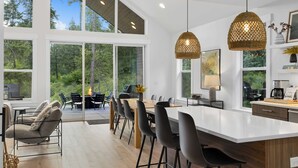 Una cocina moderna con una isla grande, luces colgantes y ventanas amplias que ofrecen vistas al exterior.
