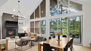 Un amplio salón con chimenea, ventanas grandes y una mesa de comedor.
