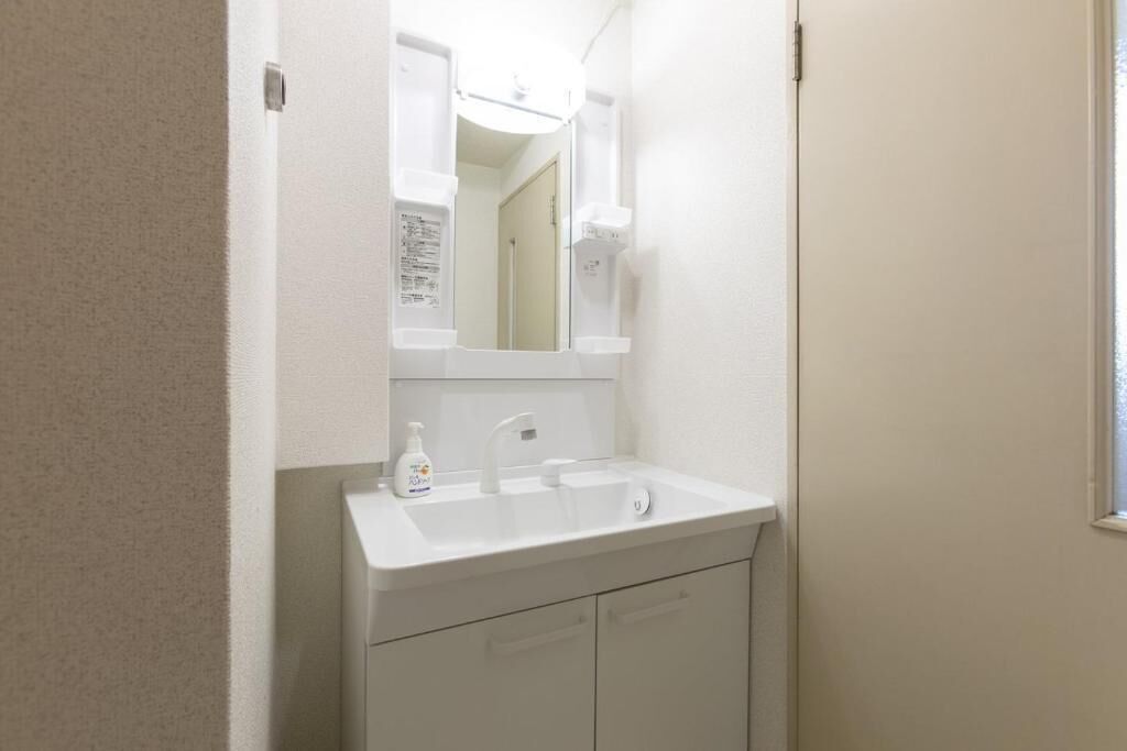 A bathroom with a white sink, mirror, and cabinet.