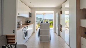 A modern kitchen with a washing machine, a dining area with a view, and a built-in oven. - L'appartement Cala Bianca (BORMES LES MIMOSAS)