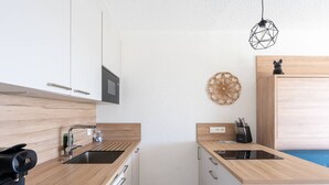 Ett kompakt kök med mikrovågsugn, diskho och en kaffemaskin.