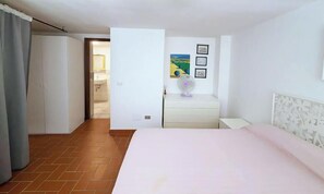 Ein Hotelzimmer mit Bett, Schreibtisch, Stuhl, Fenster und Tür.