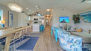 A modern kitchen with white cabinets, a central island, and blue bar stools. - Tickle My Fansea by Avantstay Mins to Shore + Private Pool + Lounge Stylish Beach House (Port Aransas)