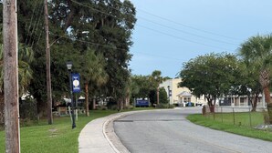 A residential street with a sidewalk, a welcome sign, and a building with a signboard. - Thunderbolt Coastal Cottage (Thunderbolt)