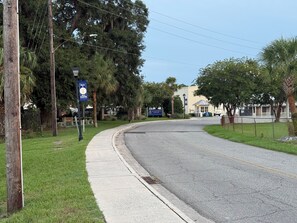 A residential street with a sidewalk, a welcome sign, and a building with a signboard. - Thunderbolt Coastal Cottage (Thunderbolt)