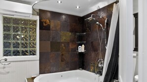 A modern bathroom with a freestanding bathtub, a shower with a rain showerhead, and a glass shower enclosure. - Thunderbolt Coastal Cottage (Thunderbolt)