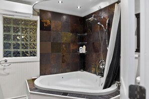 A modern bathroom with a freestanding bathtub, a shower with a rain showerhead, and a glass shower enclosure. - Thunderbolt Coastal Cottage (Thunderbolt)