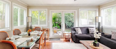 A spacious living area with a dining table, chairs, a sofa, and a ceiling fan.