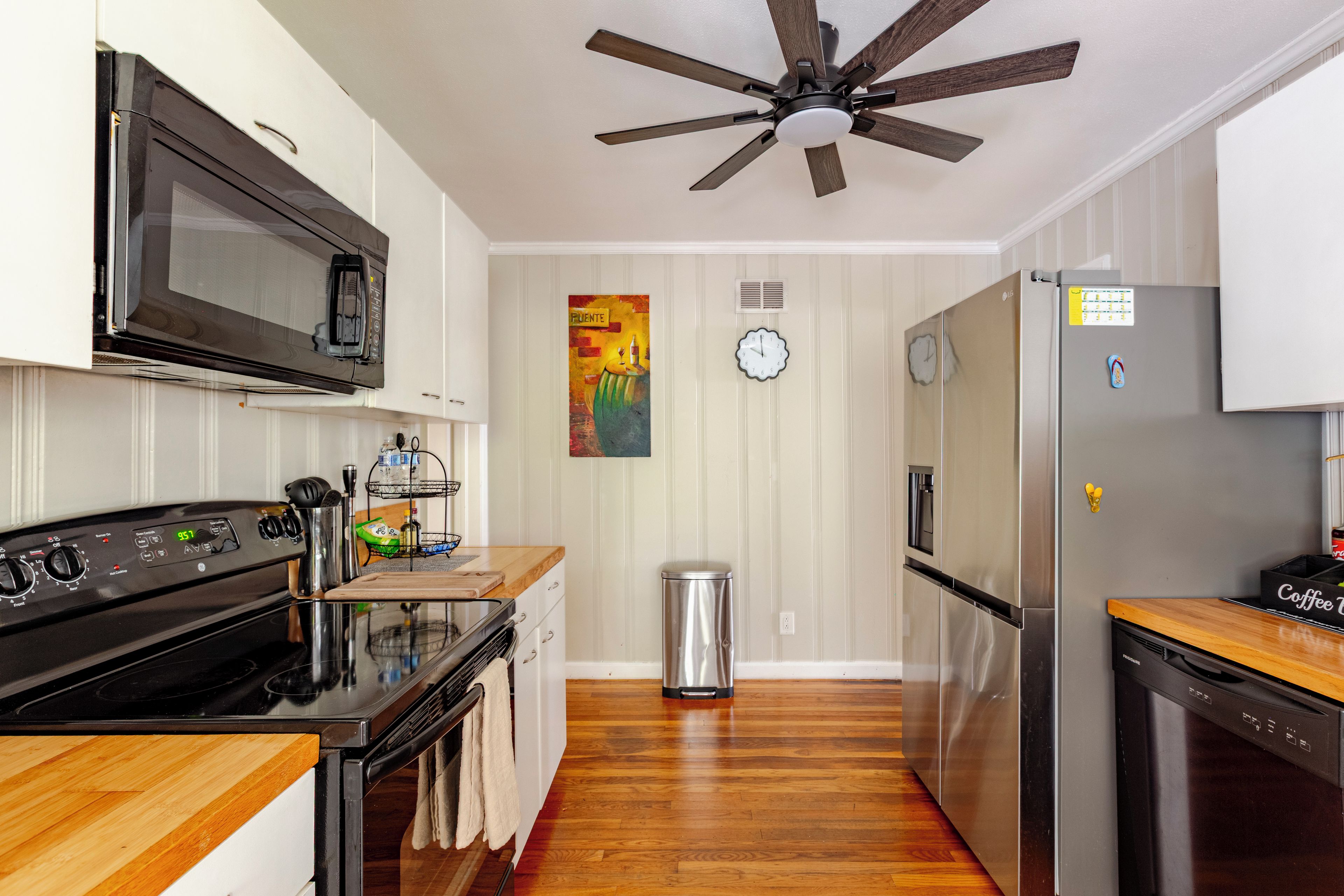 A kitchen with a microwave, stove, refrigerator, and wooden cabinets.