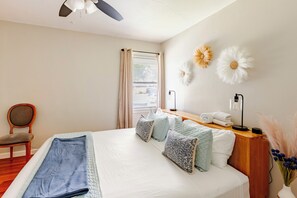 Une chambre à coucher avec un lit, une chaise, une table de chevet avec une lampe et une fenêtre avec des rideaux.